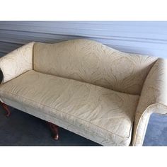 a white couch sitting on top of a floor next to a wooden table and chair