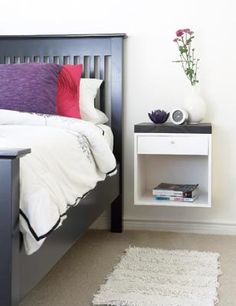 a bedroom with a bed, nightstand and flowers on the side table next to it