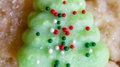 a green christmas tree cookie sitting on top of a pile of cookies