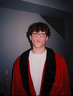 a young man wearing glasses and a red jacket