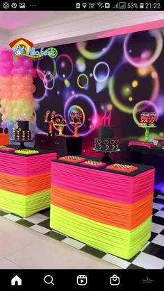 a room filled with lots of neon colored balloons and cake on top of black and white checkered flooring