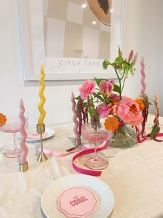 a table topped with plates and vases filled with flowers