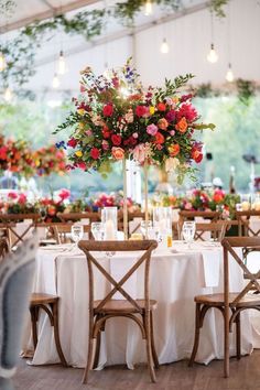 the table is set with white linens and floral centerpieces, along with wooden chairs