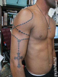 a man with a cross tattoo on his arm and chest is standing in front of a bookshelf