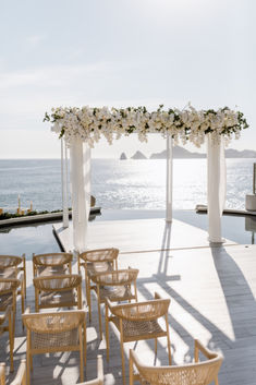 an outdoor ceremony set up with chairs and flowers on the altar by the water's edge