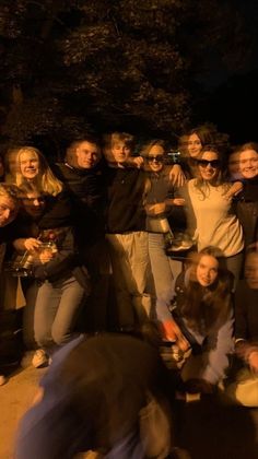 a group of people standing around each other in front of a building at night time