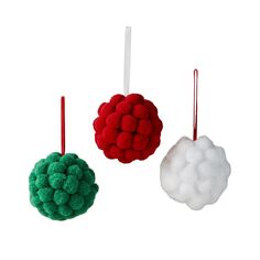 three ornaments hanging from red, white and green strings on a white background in the shape of pom - poms