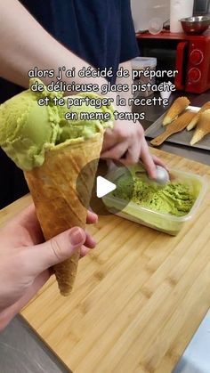 a person is scooping green ice cream into a cone on a cutting board with other food items in the background