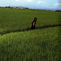 a woman walking through a lush green field