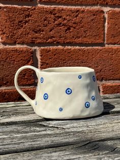 a coffee cup sitting on top of a wooden table next to a red brick wall