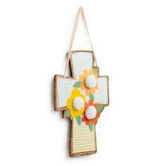 a wooden cross with flowers hanging from it's side on a white wall ornament