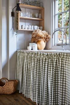 a kitchen counter with dishes and cups on it in front of a window that is open to the outside