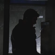 a man standing in front of a window talking on a cell phone