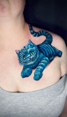 a woman with a blue cat tattoo on her chest and shoulder is looking at the camera