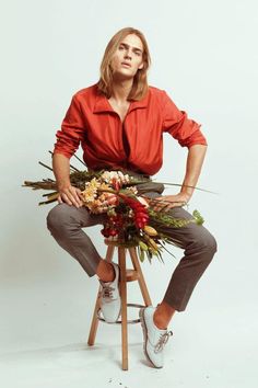 a man sitting on top of a stool holding flowers