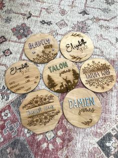 six wooden coasters with names on them sitting on a carpeted area in front of a rug