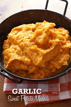 a black bowl filled with mashed potatoes on top of a checkered table cloth