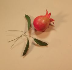 a pomegranate with green leaves on a white table top next to it