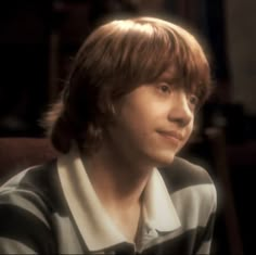 a young man with brown hair wearing a black and white striped shirt