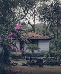 a motorcycle parked in front of a house with purple flowers on the roof and steps leading up to it