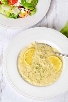 two white plates filled with soup next to a salad