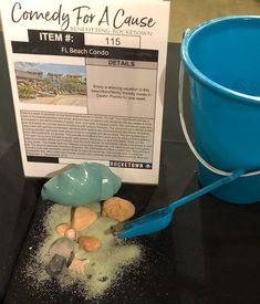 a blue bucket sitting next to a sign on top of a black table with rocks in it