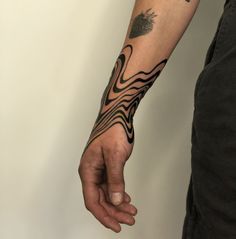 a man with a tattoo on his arm holding the hand of another person's wrist