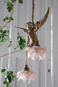 an angel figurine hanging from a chandelier with pink glass flowers on it