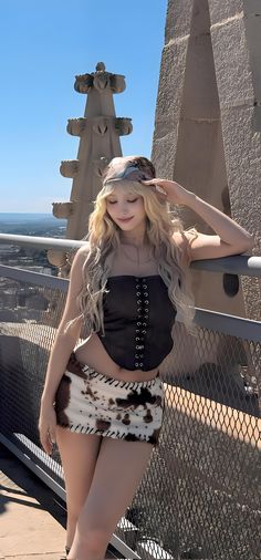 a woman is posing on the top of a building with her hair blowing in the wind