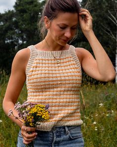 a woman holding a bouquet of flowers while standing in the grass with her hand on her head