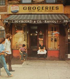 people walking on the sidewalk in front of a store