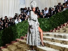 a woman in a white dress and headdress standing on steps with cameras around her