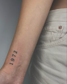 a woman's wrist with the date 2012 tattooed on her left arm and numbers in black ink