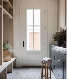 an image of a white door and some drawers in a room with two stools