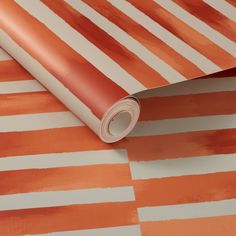 an orange and white striped wallpaper with watercolor stripes on the bottom half of it