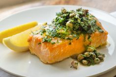 a piece of salmon on a plate with lemon wedge and parsley garnish