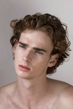 a young man with curly hair and no shirt is looking at the camera while he has his eyes closed