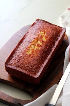 a loaf of cake sitting on top of a wooden cutting board next to a knife