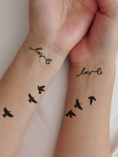 two people with matching tattoos on their arms holding each other's hands and the words love written in cursive writing