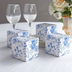 four blue and white boxes sitting on top of a table next to two wine glasses