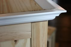 a close up view of the bottom part of a wooden cabinet with white molding