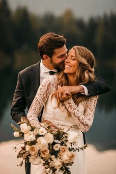 a bride and groom embracing each other in front of a lake