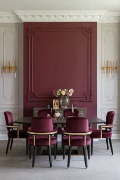 A formal dining room with a deep red accent wall, luxurious velvet chairs, and classic architectural details for an opulent and timeless look.