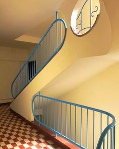 a spiral staircase in an empty room with checkered flooring and round mirrors on the wall