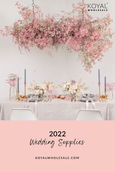 a table topped with flowers and candles next to a pink sign that says koval wedding supplies