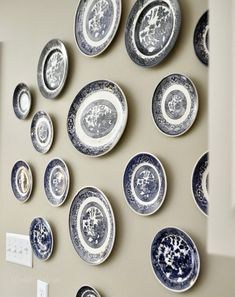 many plates are arranged on the wall near each other in blue and white designs,