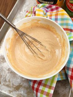 a white bowl filled with batter and whisk on top of a table next to a bottle of mayonnaise