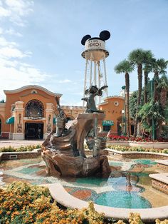 a fountain in front of a building with mickey mouse heads on it