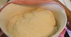 a bowl filled with dough sitting on top of a counter next to a red and white towel