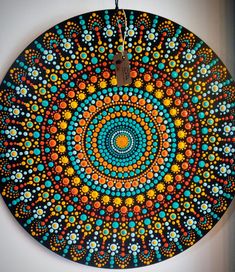 a circular painting on the wall with circles and dots in blue, orange, yellow and white